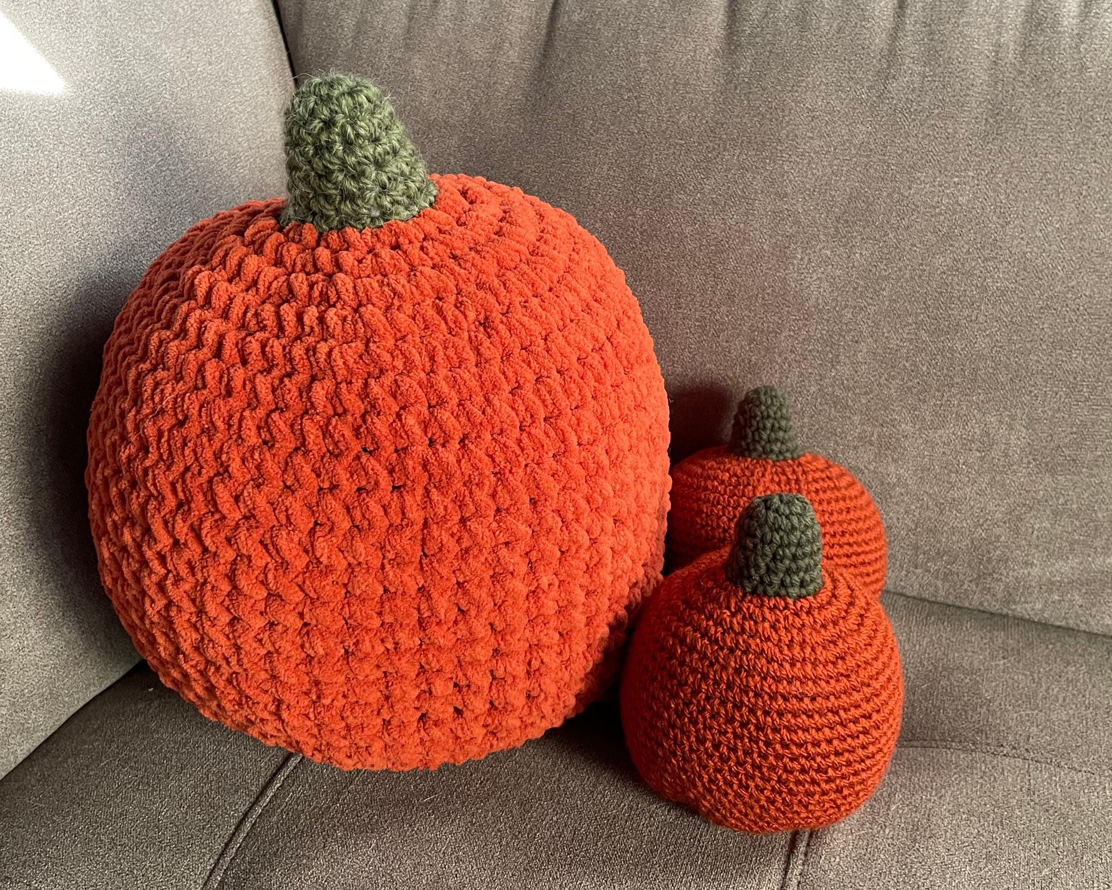 Three crocheted pumpkins on a gray surface