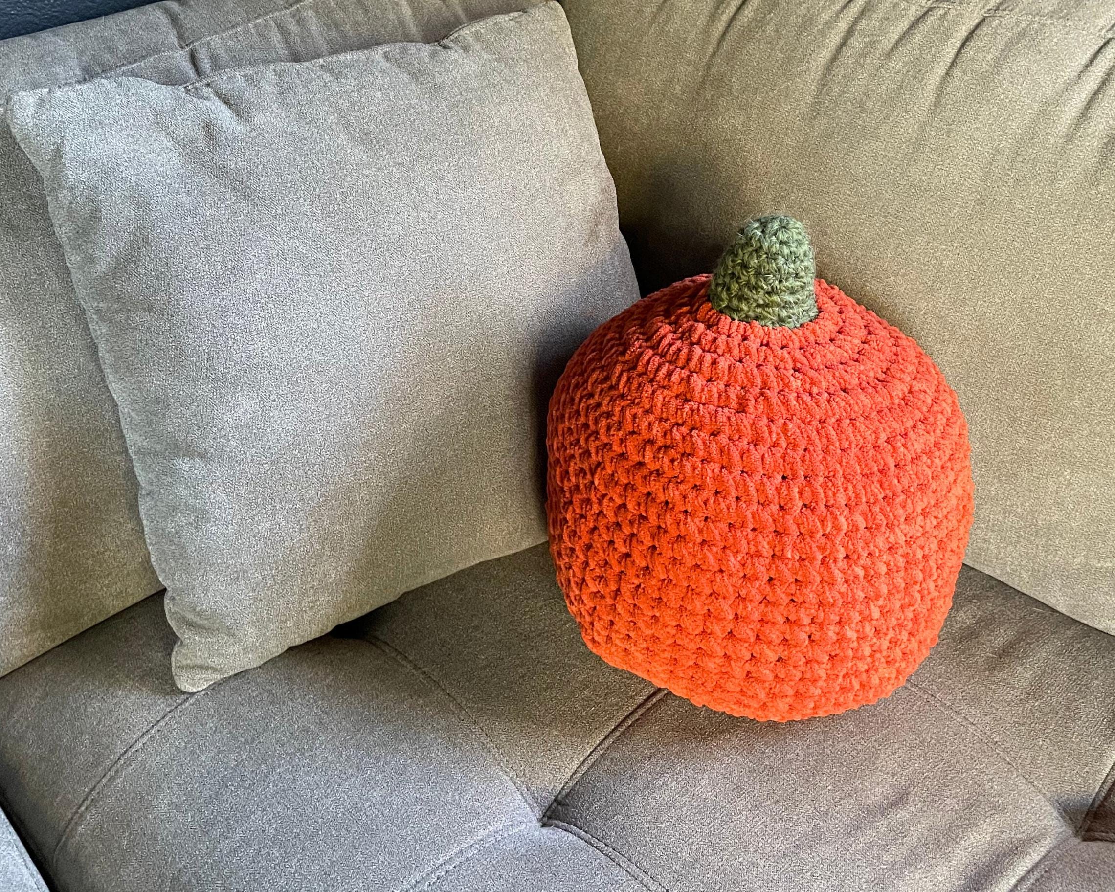 Crocheted pumpkin pillow on a beige couch